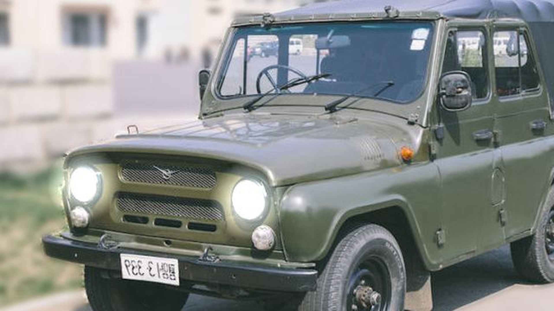 16. Corea del Norte cruza la línea, ¡El Comando de la ONU reacciona!. An olive green vintage off-road vehicle parked outdoors, featuring a distinctive classic design with round headlights and a visible license plate. Opens a video in a new window.