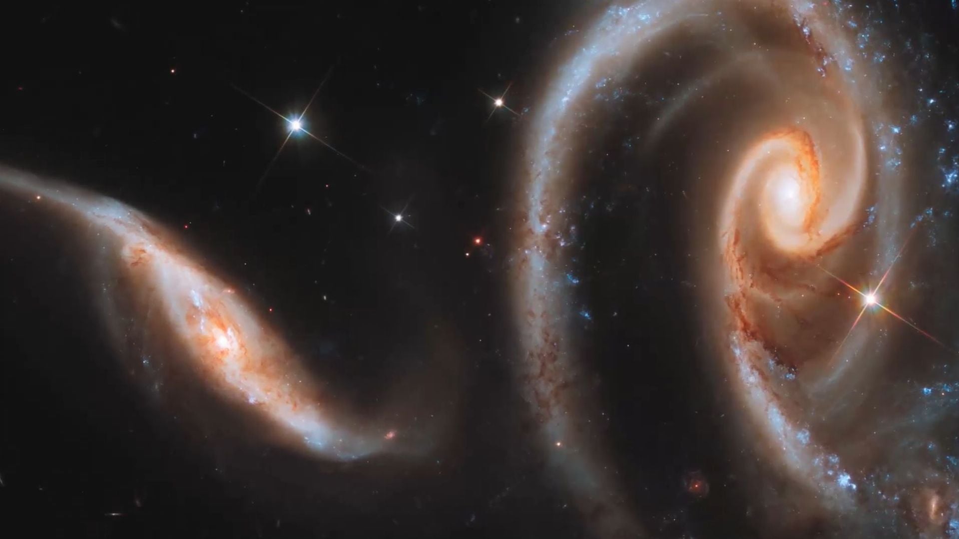 4. Er kommt auf den Wolken des Himmels.... A vivid image of several galaxies interacting in deep space, featuring swirling arms of stars and glowing centers surrounded by cosmic dust and bright star formations. Opens a video in a new window.
