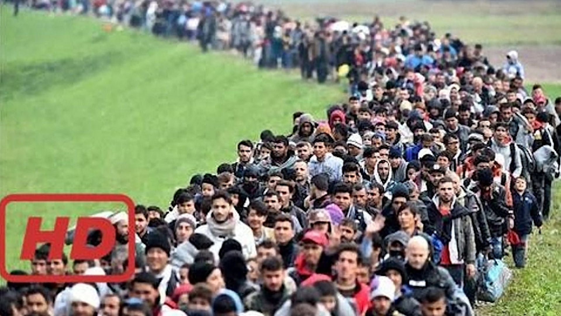 9. The Truth About Europe's Migrant Crisis. A long line of people, predominantly young men, walking through a grassy field. There is an overlay indicating "HD" on the image. Opens a video in a new window.