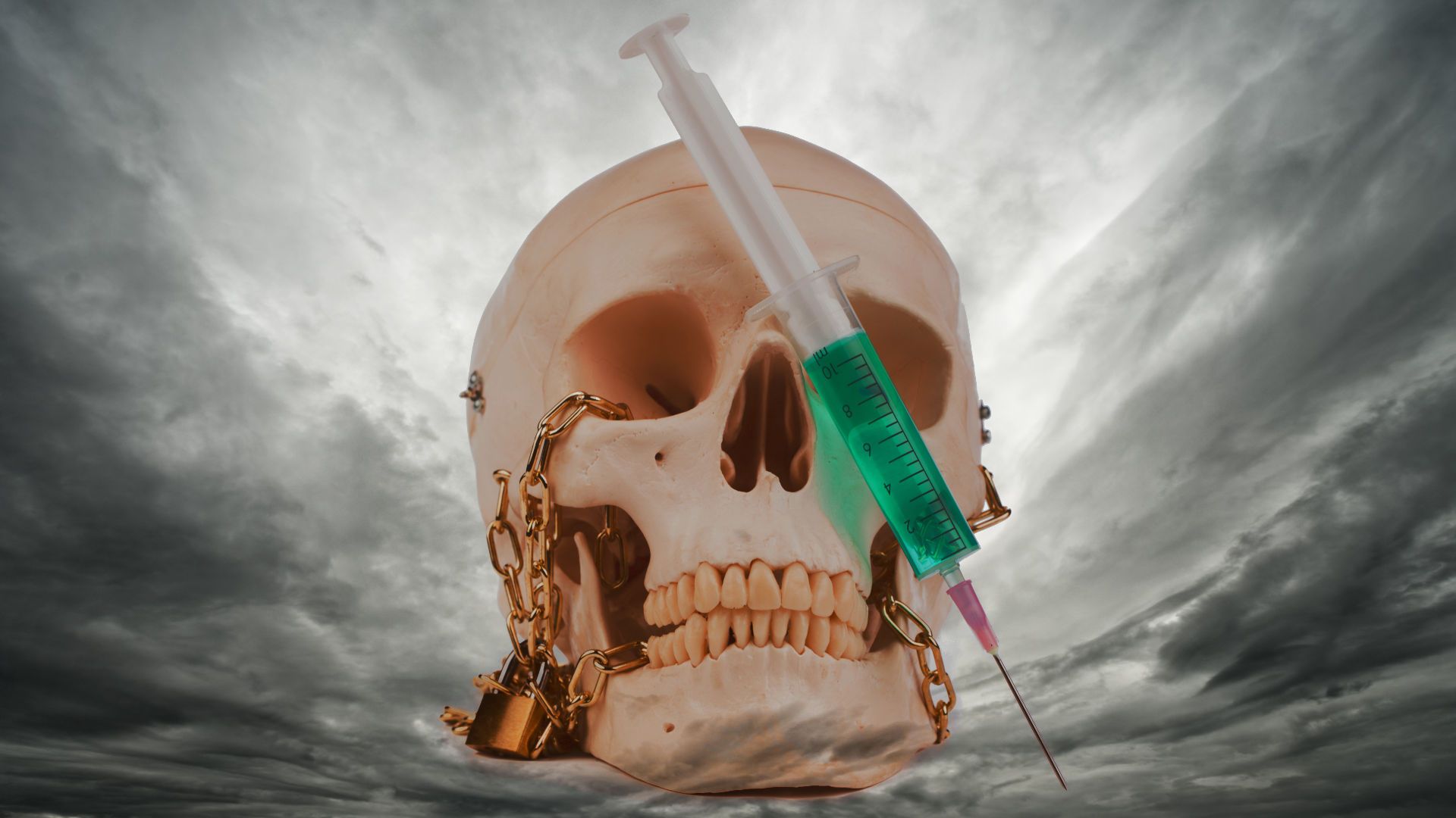 17. Die Impfstoff Plage. A surreal image featuring a human skull with gold chains hanging from it, pierced by a large green syringe against a dramatic cloudy sky. Opens a video in a new window.