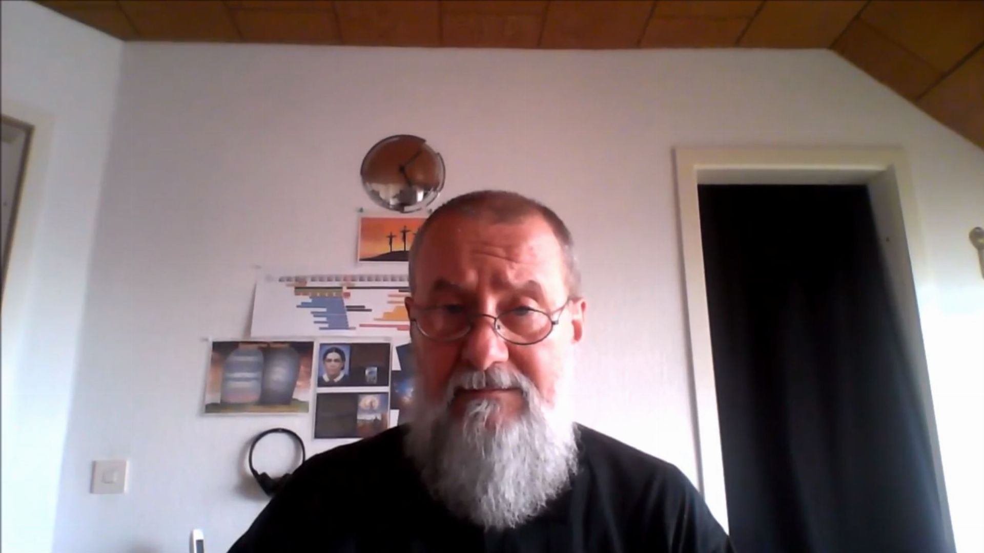 5. M87 - kleine schwarze Wolke. An elderly man with a beard sits in front of a computer in a room decorated with various scientific and astronomical objects, including a small terrestrial globe and images related to the study of the heavens. Opens a video in a new window.