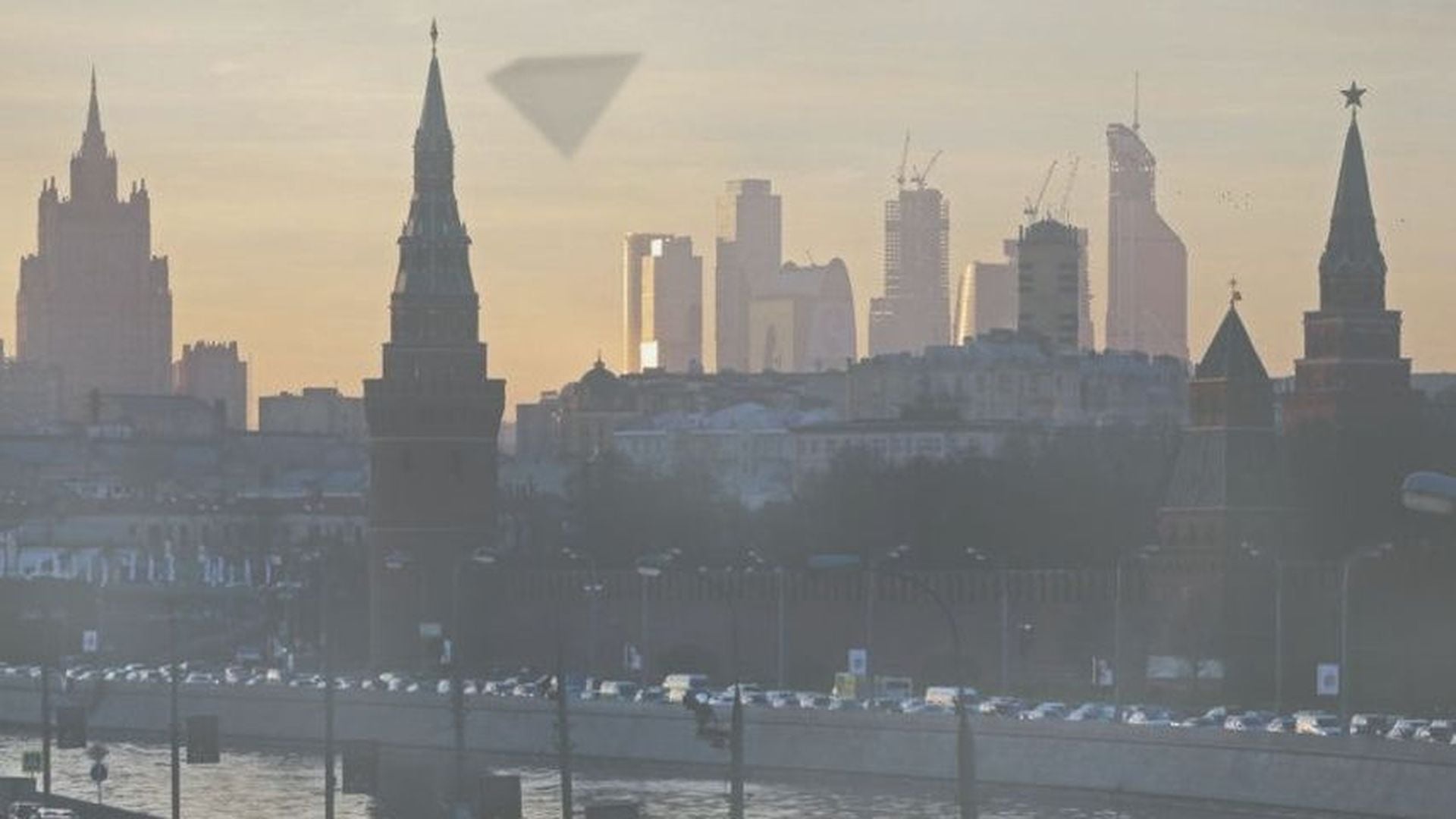 2. UFO 10-12-2009 Moskau Pyramiden UFO bei Tag. A city skyline at dawn, highlighting contrasting architectural styles with historic spires and modern skyscrapers backlit by the sun. Opens a video in a new window.