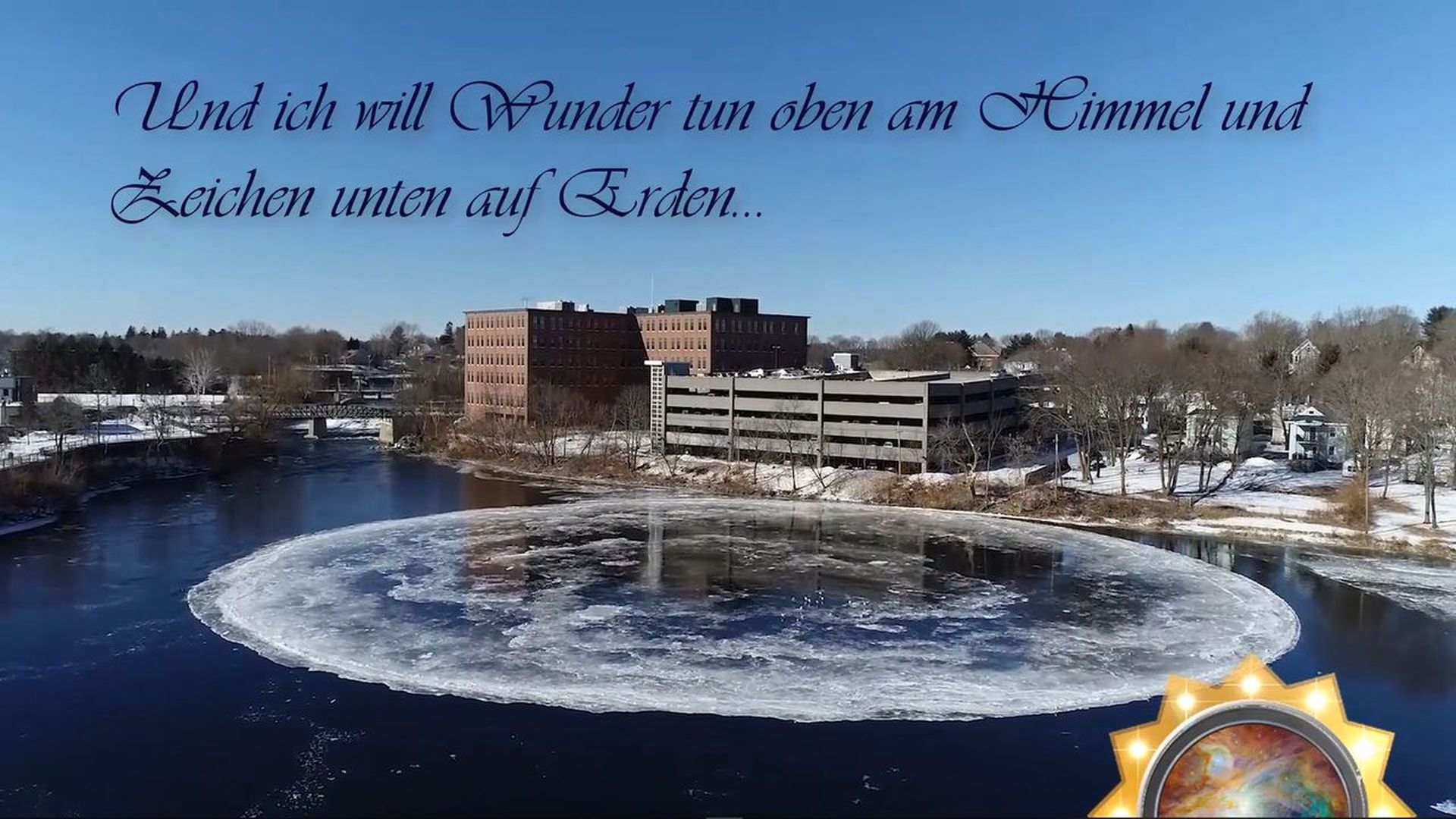 11. Die Eis-Uhr im Presumpscot. Aerial view of a frozen river with a circular ice formation in the center, surrounded by snow-covered trees and buildings under a clear blue sky. In the bottom right corner, there is an artistic depiction of a celestial symbol overlaid with an image of the sun containing intricate designs resembling the Mazzaroth. Opens a video in a new window.